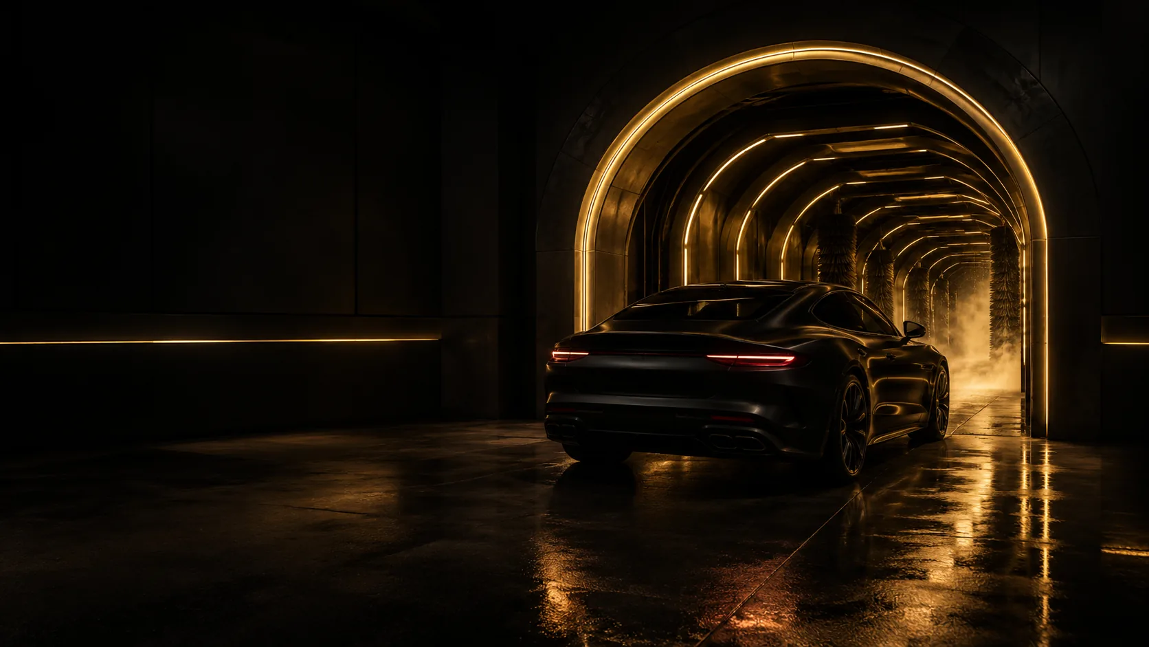 A black coupe entering the gold-lit arch of the Executive wash tunnel at night